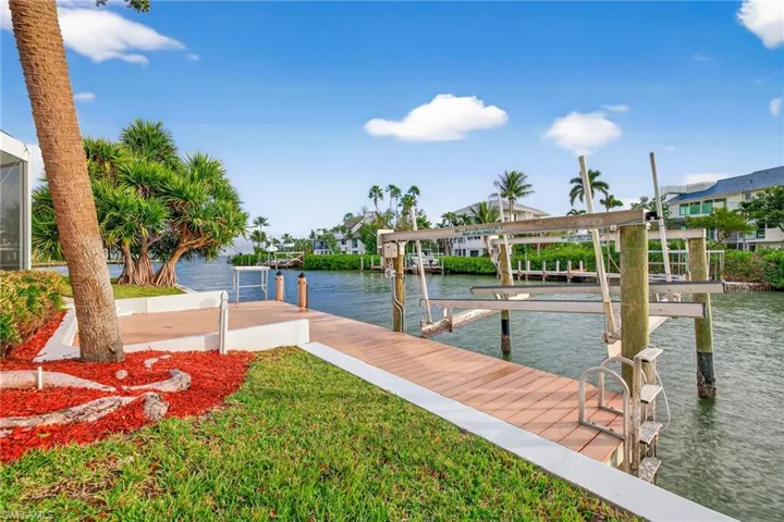 Dock area featuring a water view, boat lift, and a yard