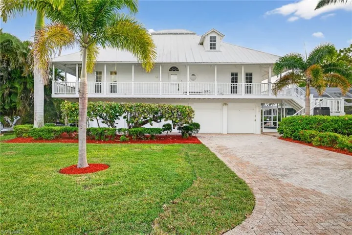 View of front facade featuring a metal roof, decorative driveway, a front lawn, an attached garage, and a balcony