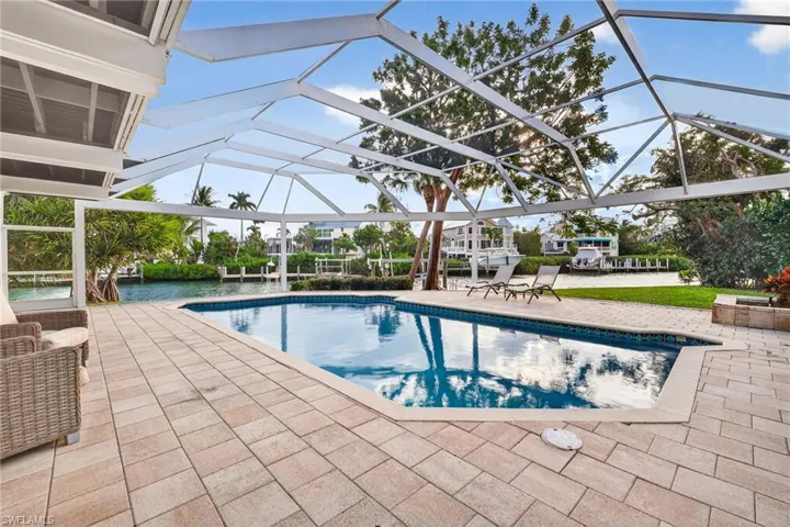 Outdoor pool featuring a patio, a sunroom, and glass enclosure