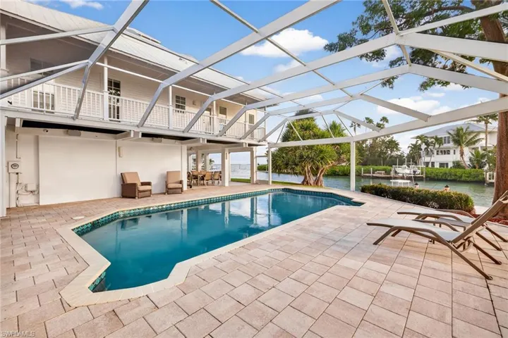 Outdoor pool featuring a patio area, a lanai, a sunroom, and a water view