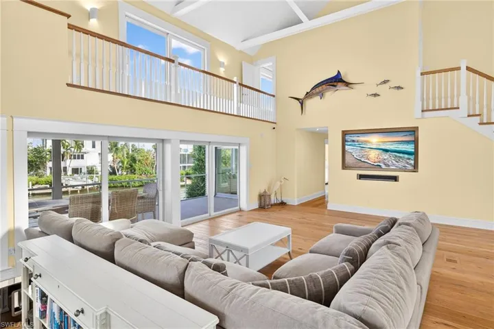 Living room with light wood-type flooring, beamed ceiling, stairs, and high vaulted ceiling