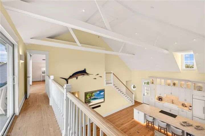 Hall featuring healthy amount of natural light, beamed ceiling, light wood-style floors, and high vaulted ceiling