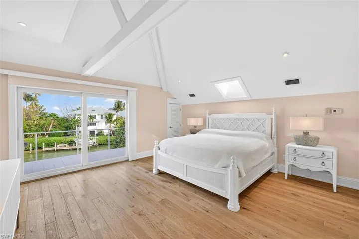 Bedroom with a skylight, light wood-type flooring, access to outside, a water view, and recessed lighting