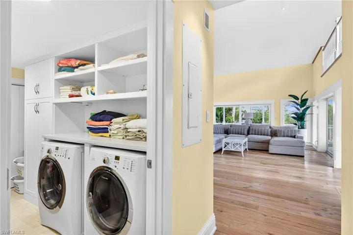 Laundry area featuring independent washer and dryer, electric panel, a high ceiling, and light wood-style flooring