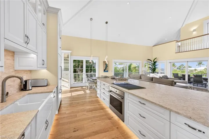 Kitchen featuring white cabinetry, decorative light fixtures, high vaulted ceiling, oven, and light wood-style flooring