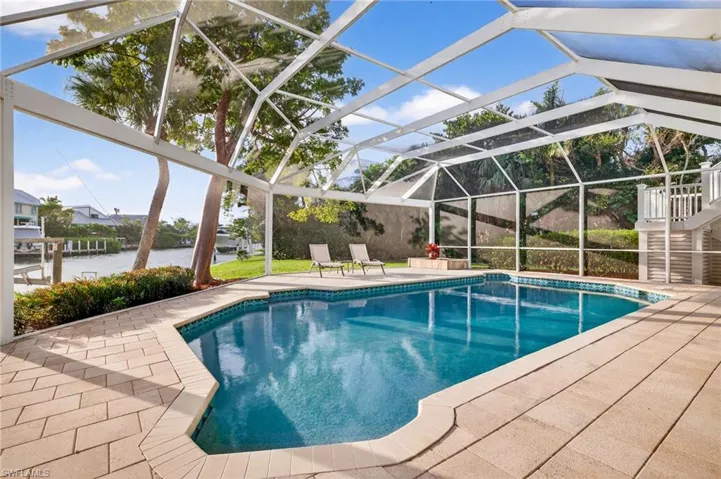 Swimming pool with glass enclosure, a patio area, and a sunroom