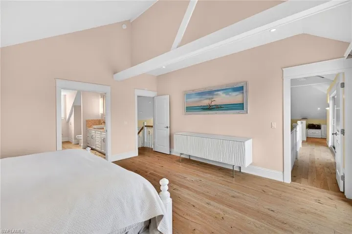 Bedroom featuring light wood-style floors, ensuite bathroom, high vaulted ceiling, and recessed lighting