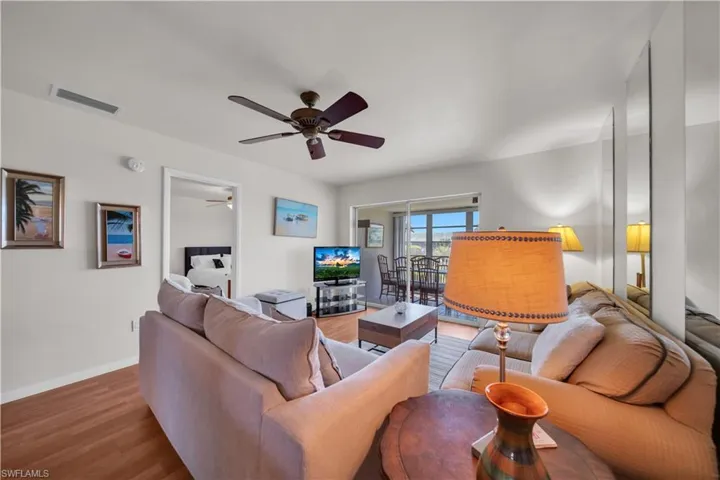 Living area featuring wood-finish flooring, a ceiling fan, and sliding glass door access to an exterior space