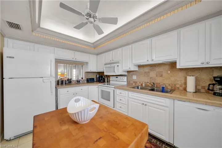 Kitchen featuring white cabinetry, light-colored countertops, and a patterned tile backsplash