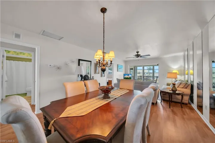 Dining area featuring a wood-finish table, a traditional chandelier, and wood-finish flooring