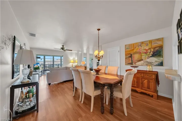 Dining area with wood-finish flooring, featuring a chandelier, and a white paneled door