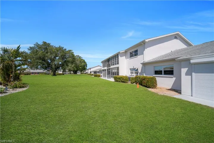 Expansive green lawn with mature trees and tropical landscaping