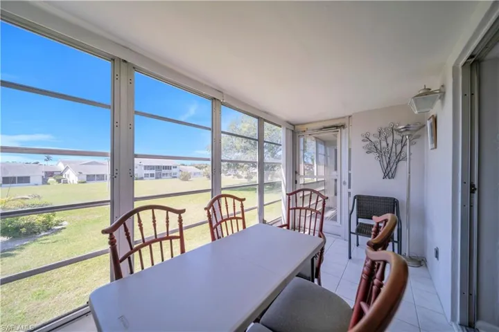 Screened sunroom featuring large windows, white ceiling, white tile flooring, and white walls