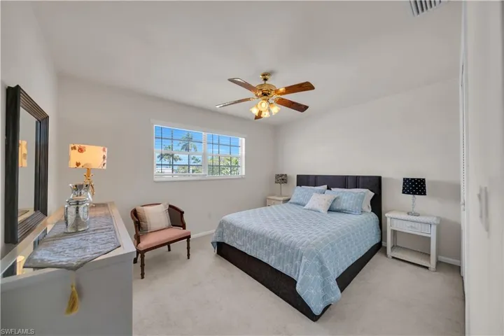 Carpeted room with a multi-pane window, ceiling fan with light fixture, and neutral wall tones