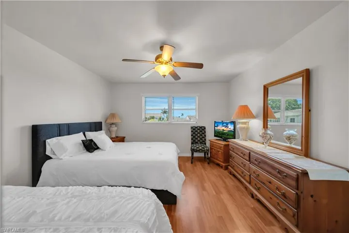 Bright interior space featuring wood-finish flooring, a ceiling fan with integrated lighting, and multiple windows with horizontal blinds