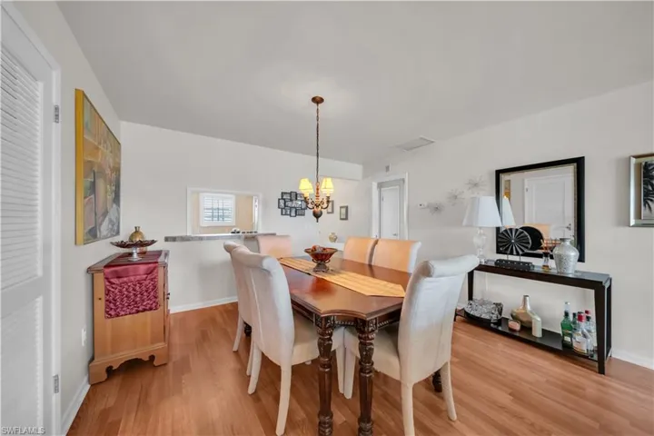 Dining area featuring warm wood-finish flooring, a pass-through window with a countertop, and recessed lighting