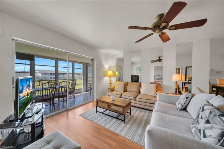 Living area with wood-finish flooring, a ceiling fan, and mirrored wall accents