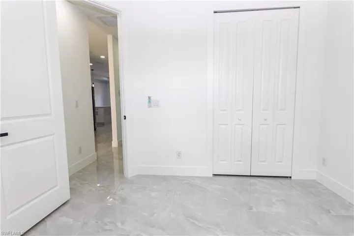 Bedroom featuring light marble finish floors and a closet