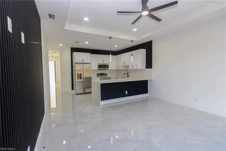 Kitchen featuring stainless steel appliances, a peninsula, white cabinets, modern cabinets, and decorative light fixtures