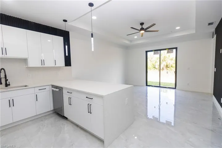 Kitchen with white cabinets, light marble finish flooring, tasteful backsplash, open floor plan, and a peninsula