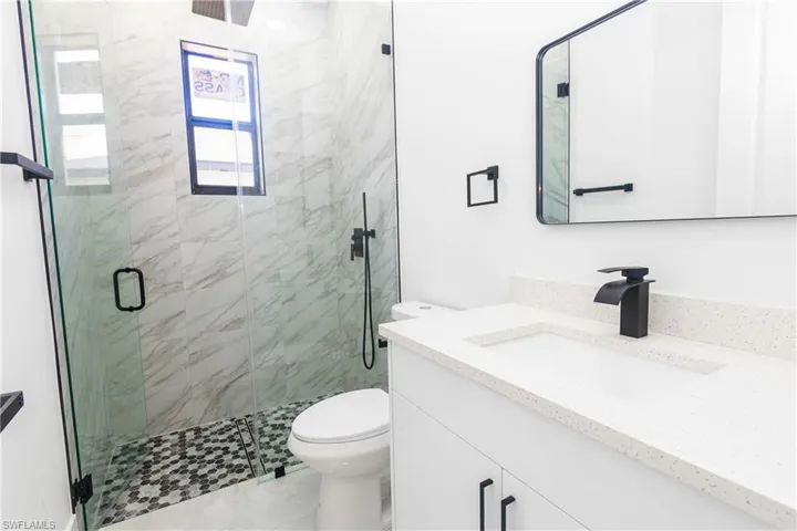 Full bath featuring vanity and a marble finish shower