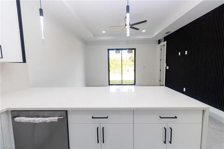 Kitchen with white cabinets, stainless steel dishwasher, light stone countertops, a peninsula, and recessed lighting