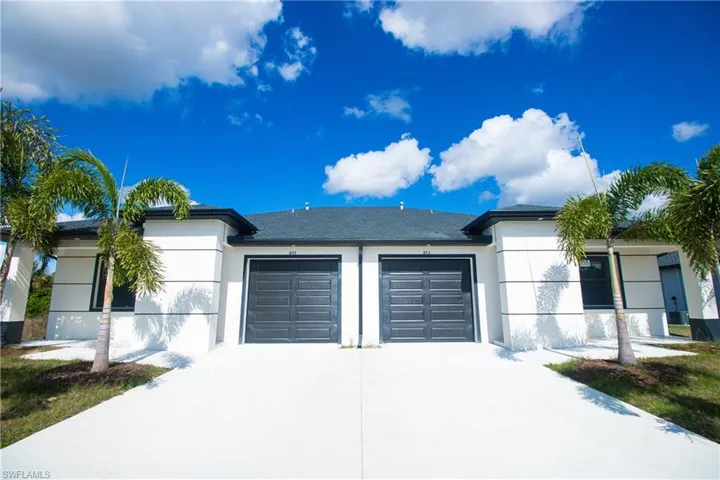 View of front facade featuring stucco siding, an attached garage, and driveway
