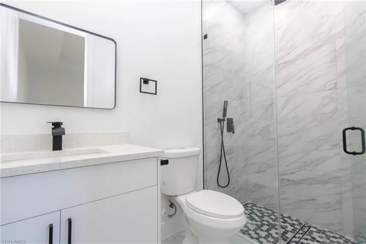 Bathroom with vanity and a marble finish shower