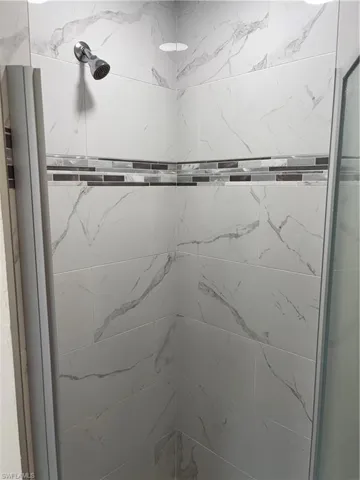 Tiled Master bath walk-in shower with accent tile and glass door entry