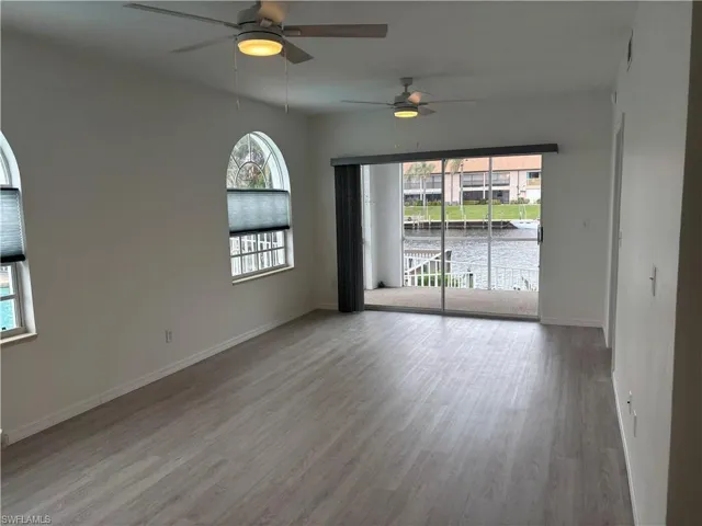 Spacious open living area features 2 ceiling fans and new LVP flooring, opening onto the screened lanai