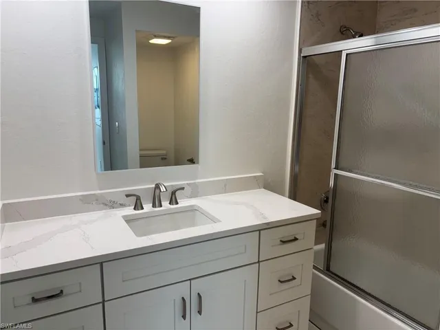 Guest bath features wood cabinetry, granite countertops and  a combination tub / shower