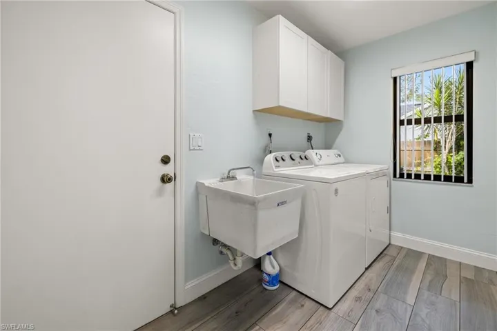 Laundry room featuring light hardwood / wood-style floors, cabinets, sink, and washing machine and dryer