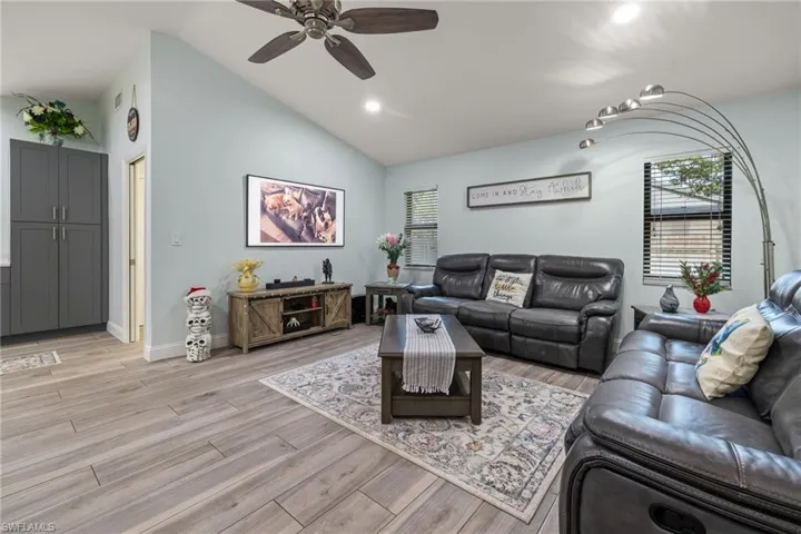 Living room featuring vaulted ceiling, light hardwood / wood-style flooring, and ceiling fan