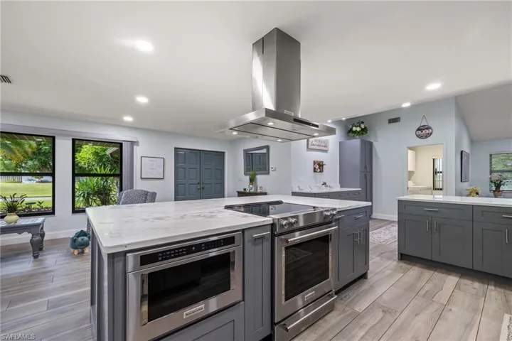 Kitchen featuring gray cabinetry, a center island, light wood-type flooring, appliances with stainless steel finishes, and extractor fan