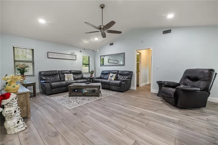 Living room with ceiling fan, plenty of natural light, vaulted ceiling, and light hardwood / wood-style flooring