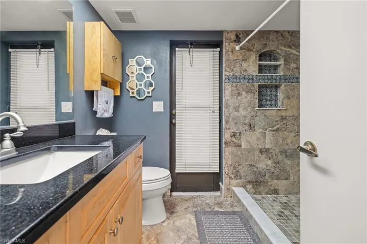 Bathroom with a tile shower, vanity, and toilet