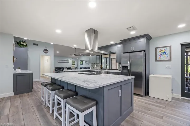 Kitchen with stainless steel fridge with ice dispenser, island range hood, light hardwood / wood-style flooring, and gray cabinetry