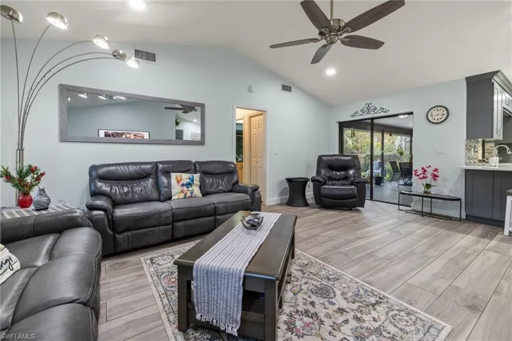 Living room with ceiling fan, vaulted ceiling, and light hardwood / wood-style flooring