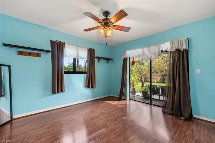 Empty room featuring dark hardwood / wood-style flooring, ceiling fan, and a healthy amount of sunlight