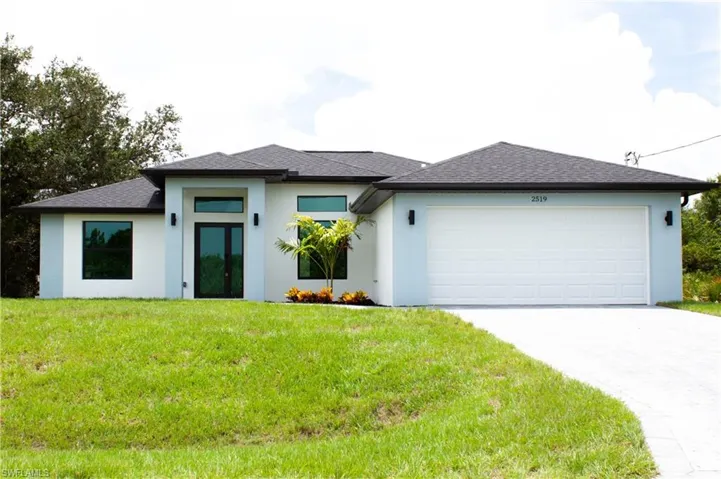 View of front of home with a garage, concrete driveway, roof with shingles, stucco siding, and a front yard
