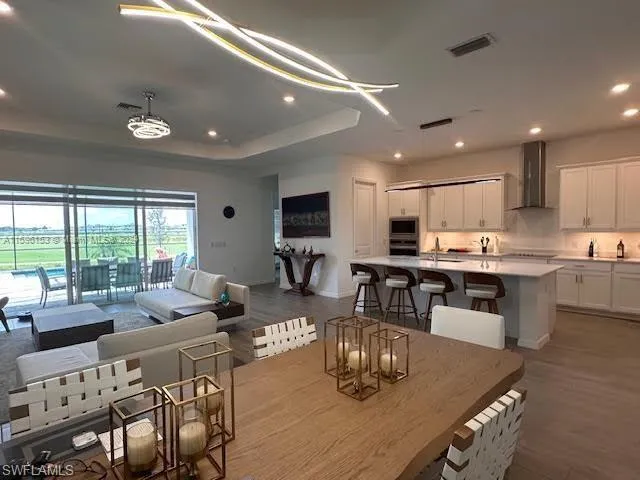 Dining space featuring sink, a tray ceiling, and wood-type flooring