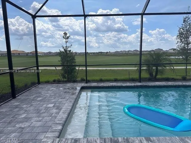 View of pool with glass enclosure and a patio area