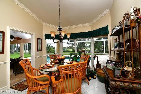 Dining space featuring a chandelier, plenty of natural light, light tile patterned floors, and crown molding