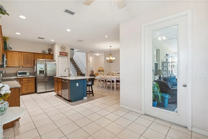 Kitchen featuring sink, hanging light fixtures, an island with sink, a kitchen bar, and appliances with stainless steel finishes