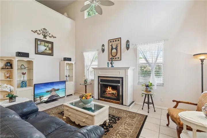 Living room featuring ceiling fan, light tile patterned flooring, and a high ceiling