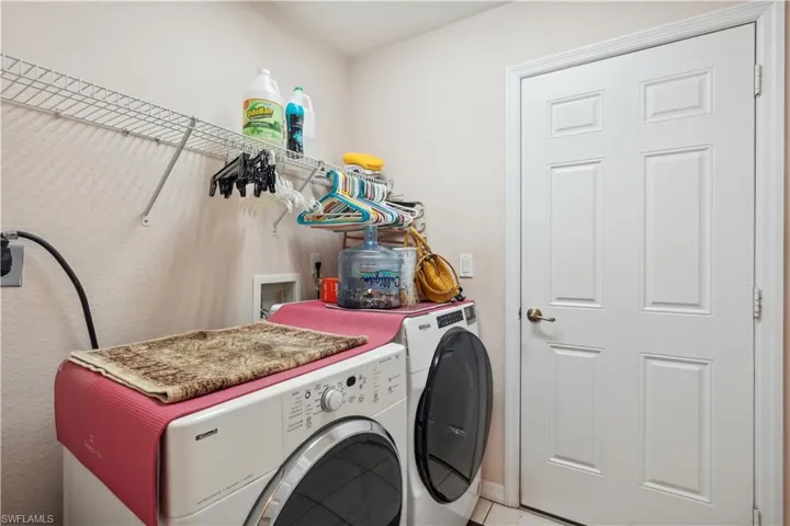 Washroom with washer and clothes dryer and light tile patterned floors