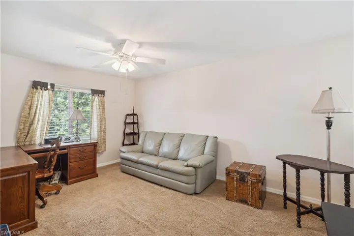 Carpeted office featuring ceiling fan