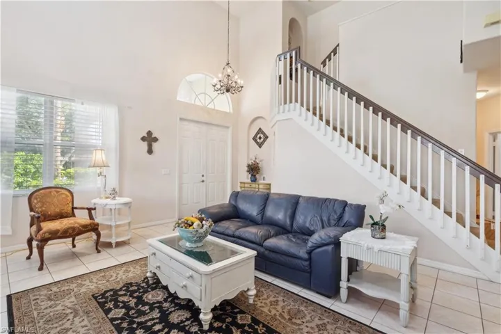 Living room with light tile patterned floors, a high ceiling, and a notable chandelier