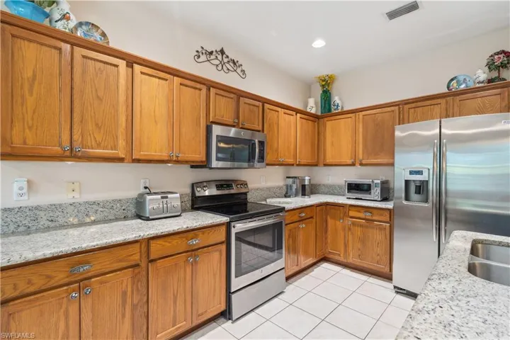 Kitchen with light stone counters, light tile patterned floors, and stainless steel appliances