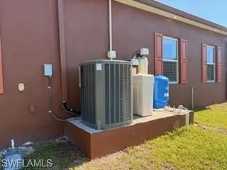 Exterior wall featuring a large air conditioning unit and water treatment system on a concrete pad